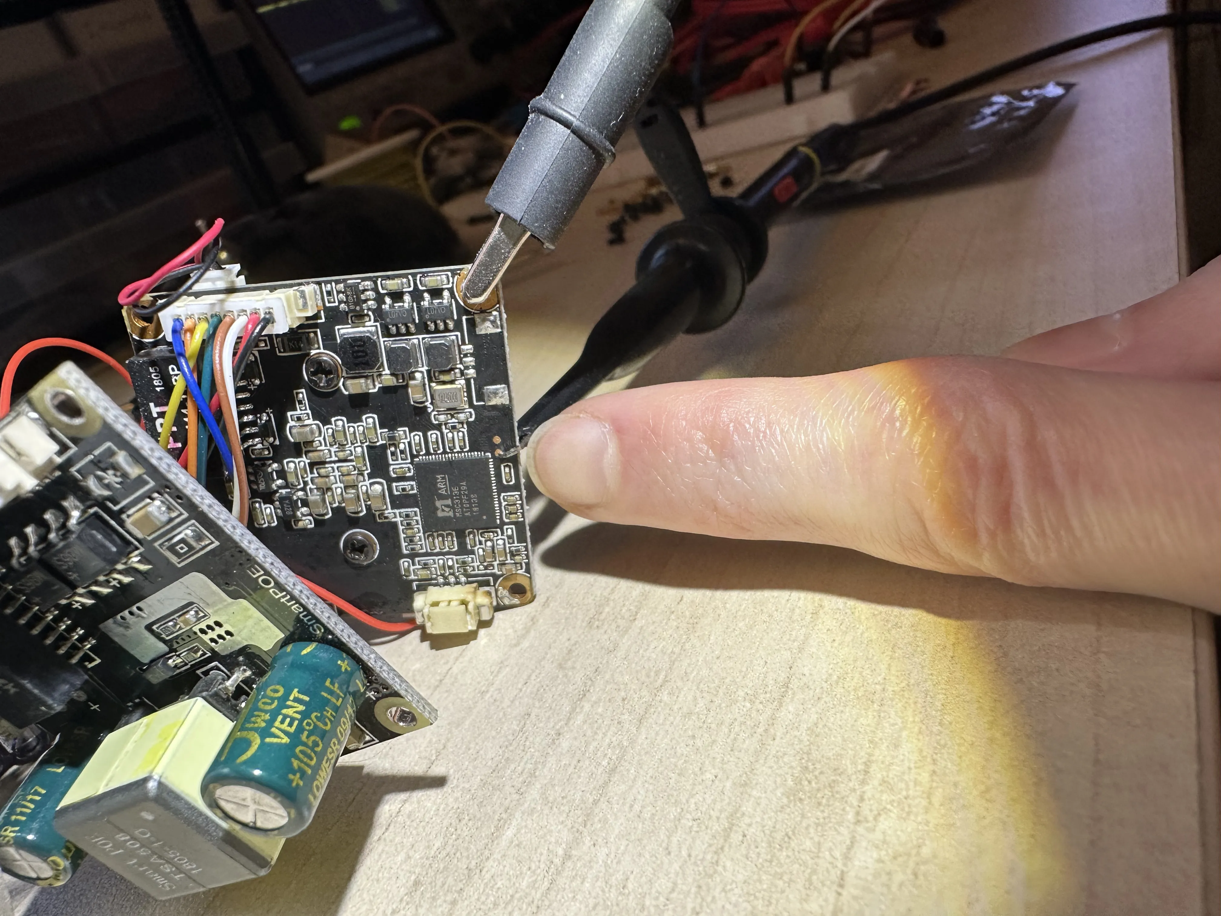 A copper pad near the processor is being probed with an oscilloscope probe. I am pointing to that pad.