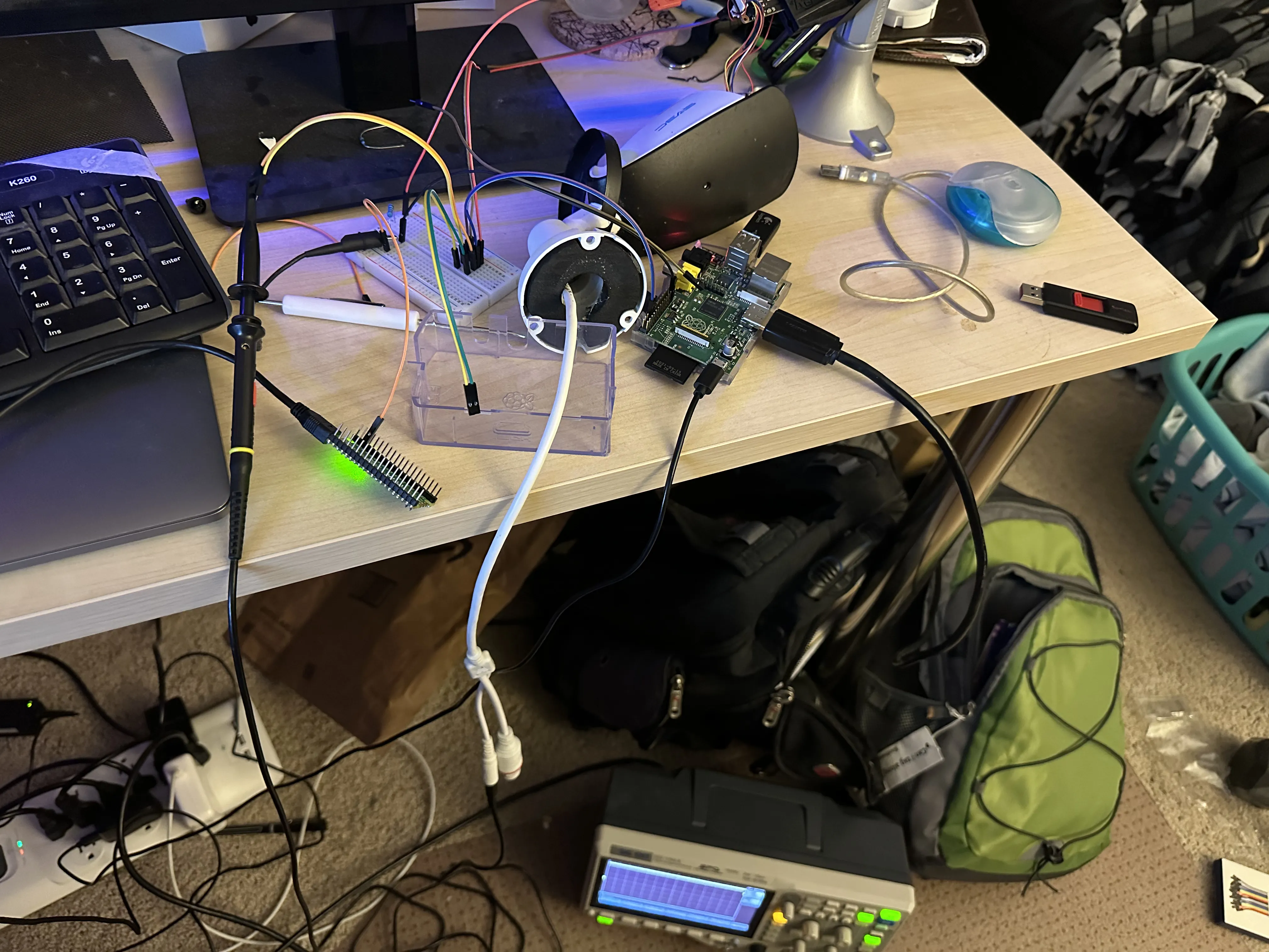 Wires from the IP camera, to a breadboard, to my Raspberry Pi 1st gen and to my Pi Pico. There is an oscilloscope sitting strangely on the ground...