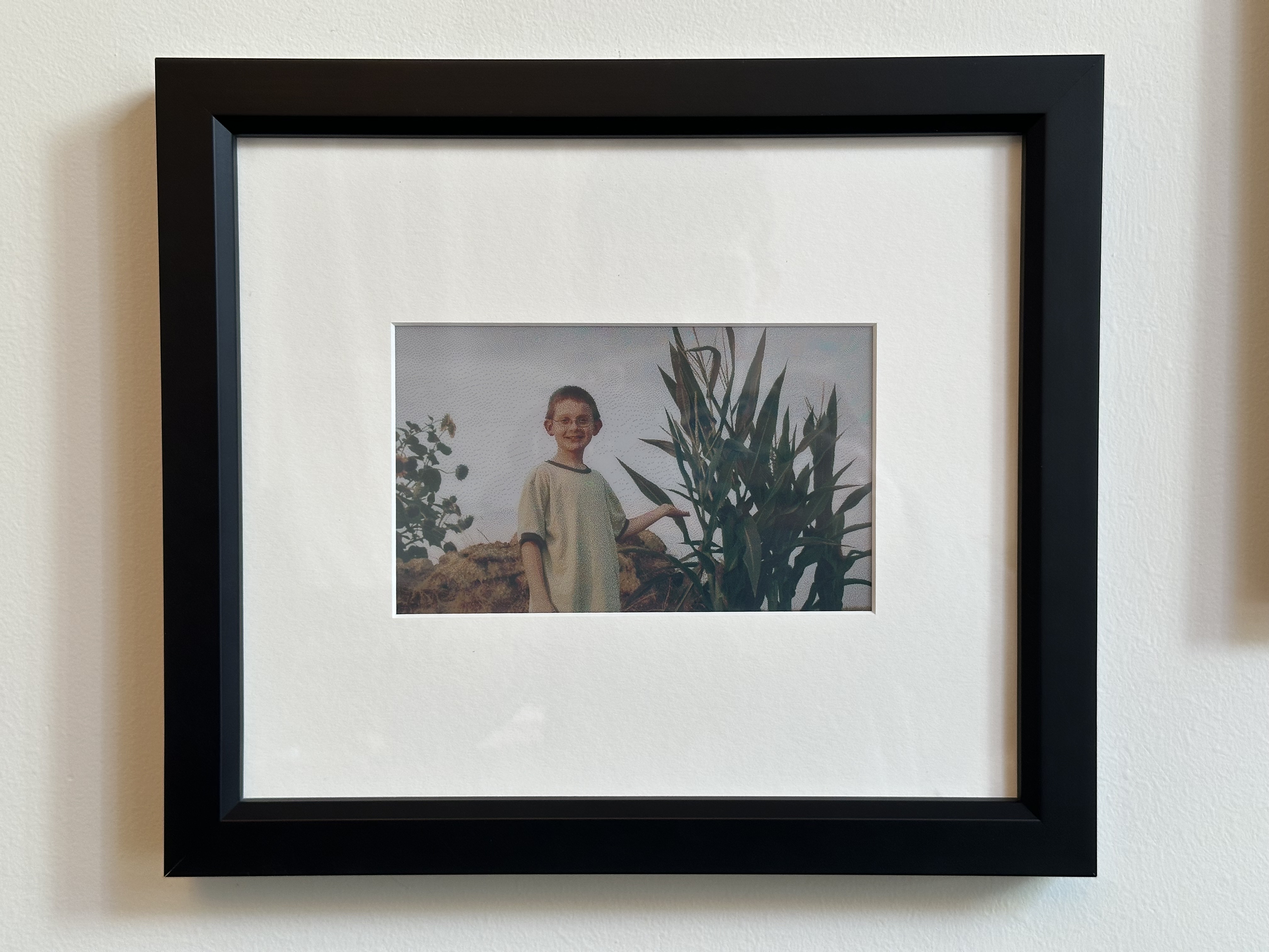 A front view of the frame, showing the black wooden border and white matte.