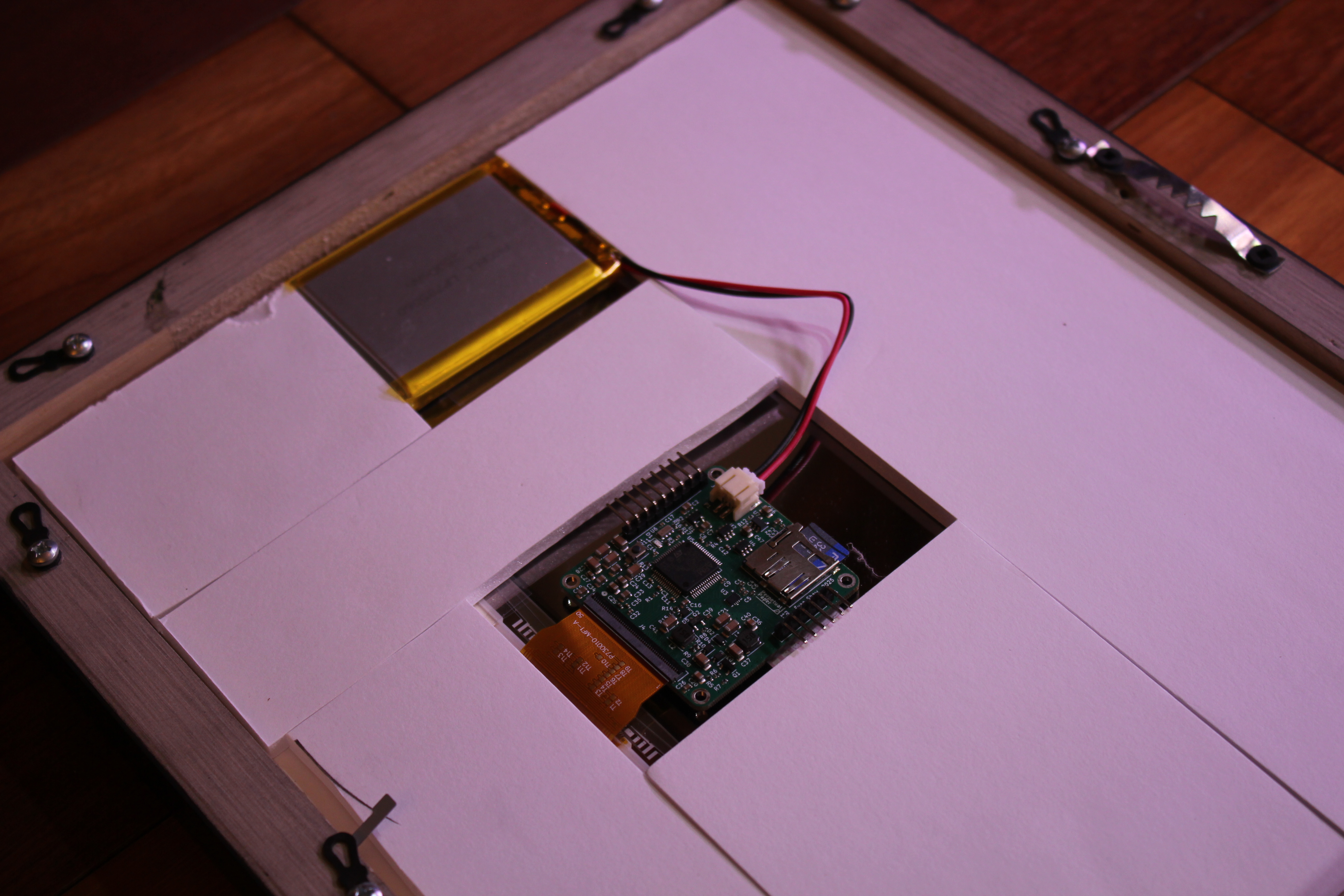 A view of the back of the Perpetual Paper in the frame; there is a battery connected to the main board, and the board is also connected to the display via a Flat Flex Connector.